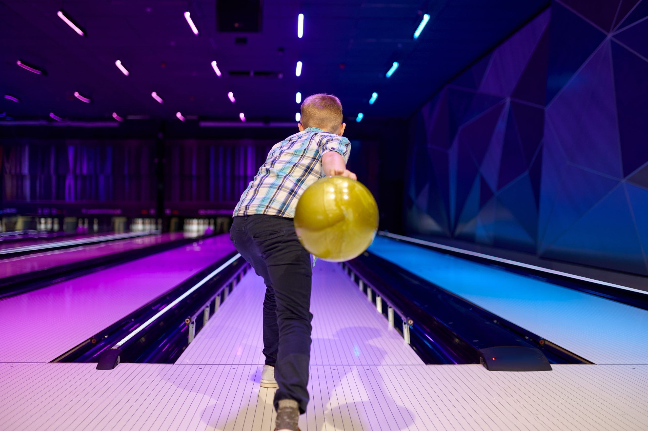 Boy holds a ball at the lane in bowling alley Boy holds a ball at the lane in bowling alley